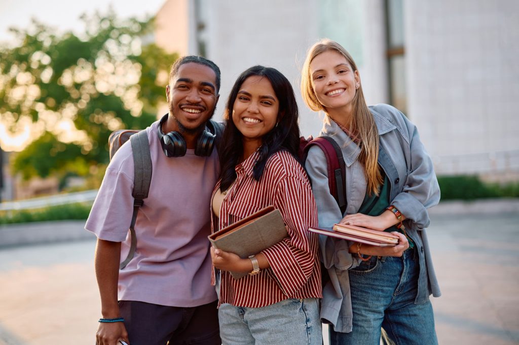 Multiracial group of happy college friends outdoors looking at camera.