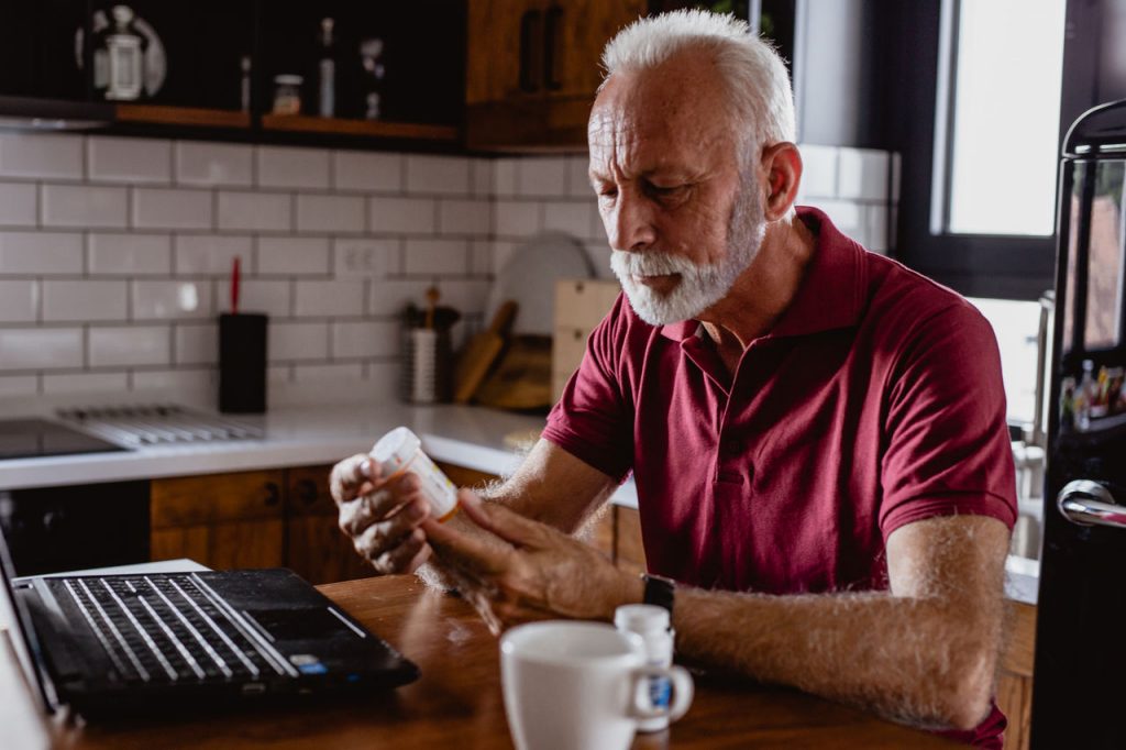 white man looking at prescription bottle