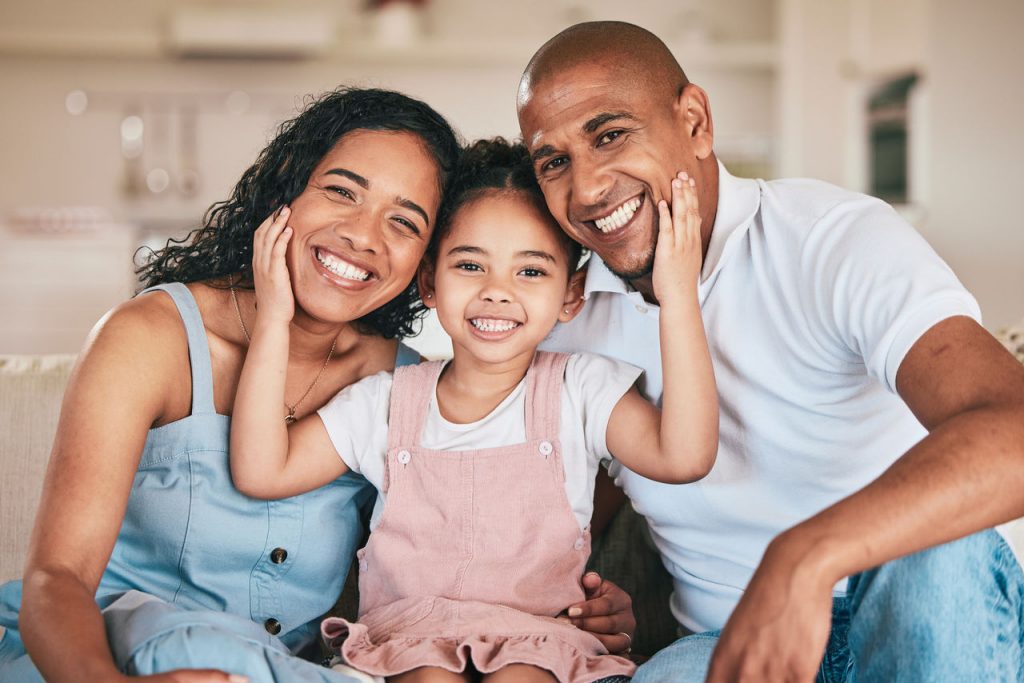 young hispanic family smiling with daughter in the middle of parents