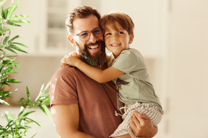 Portrait of happy single father holding his loving boy at home.