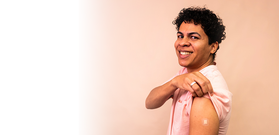 hispanic man holding shirt showing vaccine bandaid