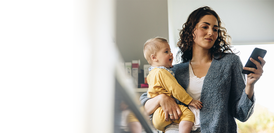 Mom holding baby looking at a phone