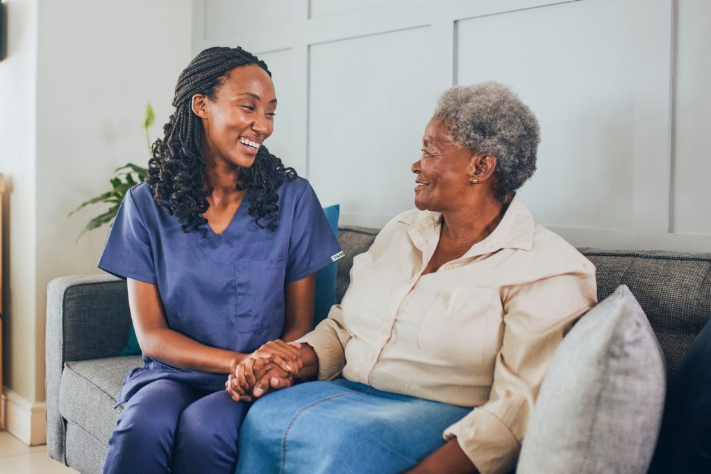 Portrait of smiling young nurse consoling and holding hands with senior woman