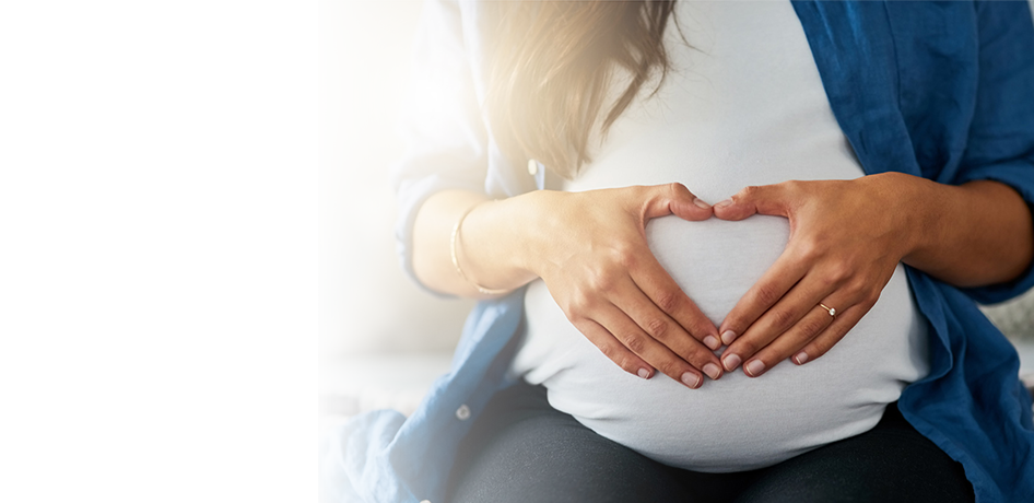 woman making heart on pregnant stomach