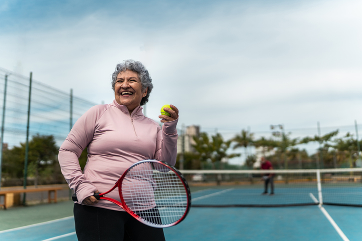 Senior woman playing tennis at sports court